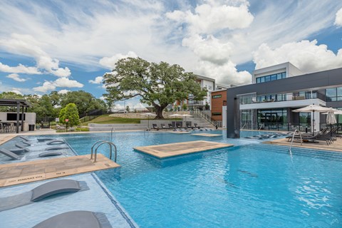 A large outdoor swimming pool with a wooden deck and lounge chairs.
