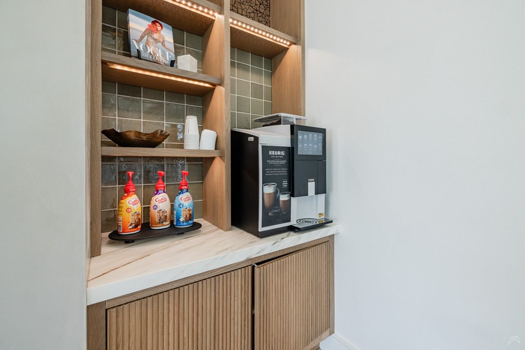 A coffee machine is on a counter with a tray of bottled drinks.
