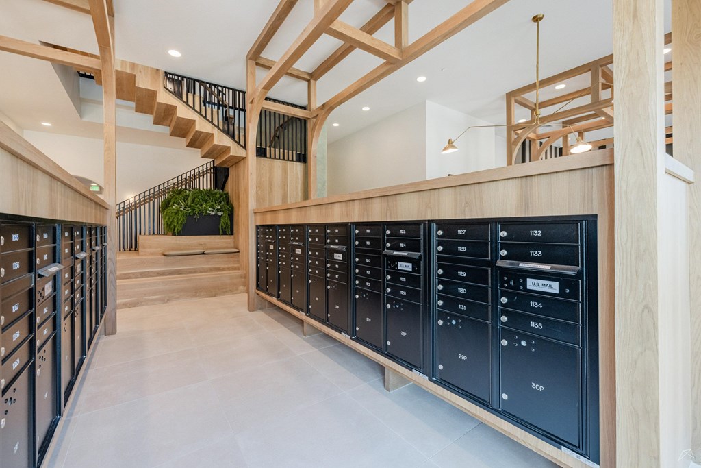 A long hallway with a staircase and mailboxes on the wall.