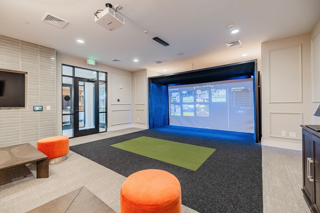 A room with a screen and orange stools.