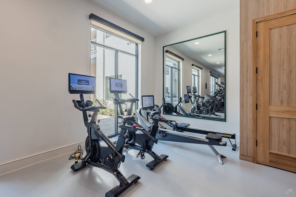 A room with a mirror, a treadmill, and a stationary bike.