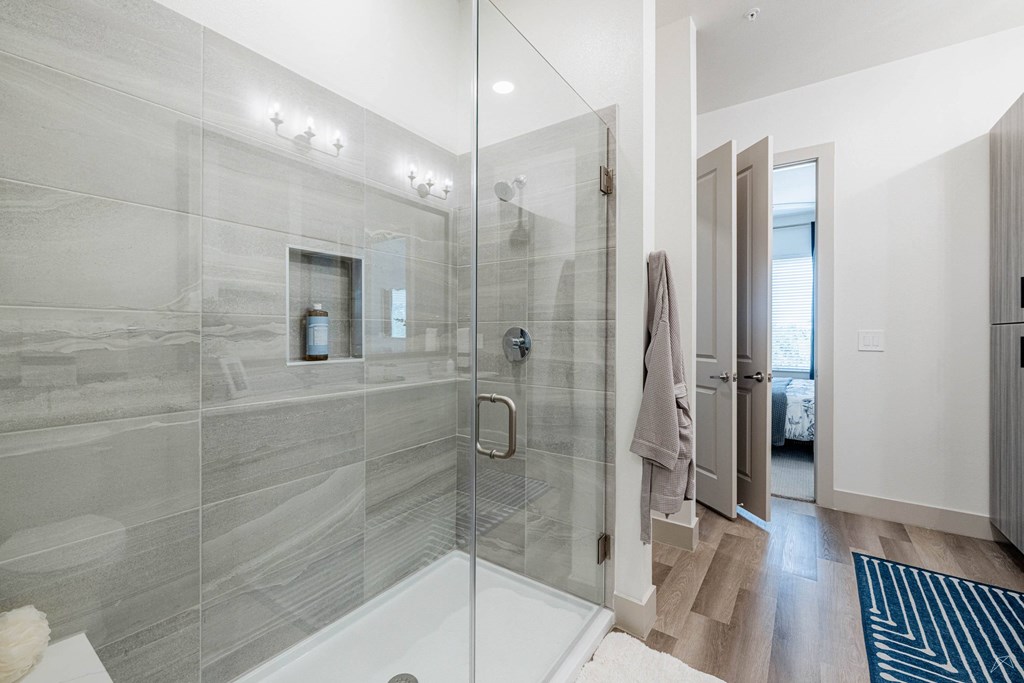 A modern bathroom with a walk-in shower and a glass door.