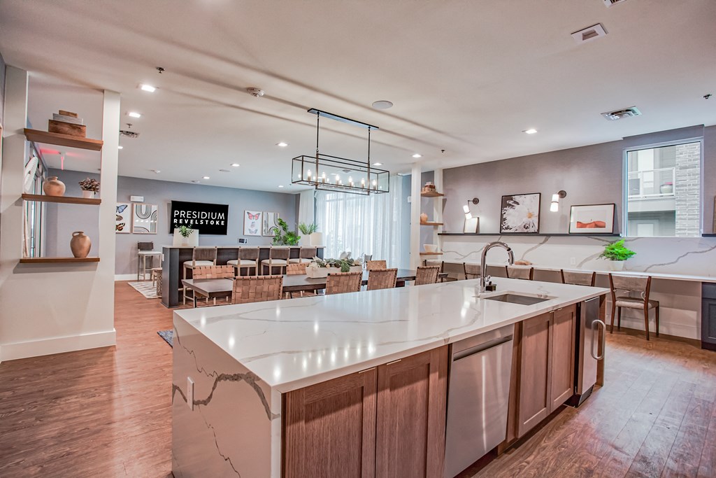 an open kitchen with a large center island and a dining room with tables and chairs  at Presidium Revelstoke, Fort Worth, TX