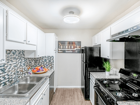A kitchen with black appliances and white cabinets.