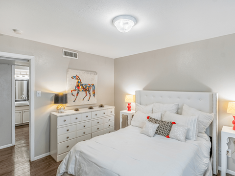 A bedroom with a large bed, a dresser, and a painting on the wall.