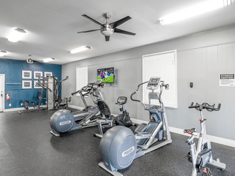 A spacious gym with a variety of exercise equipment including treadmills, stationary bikes, and weight machines.