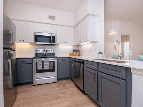 A modern kitchen with dark blue cabinets and stainless steel appliances.