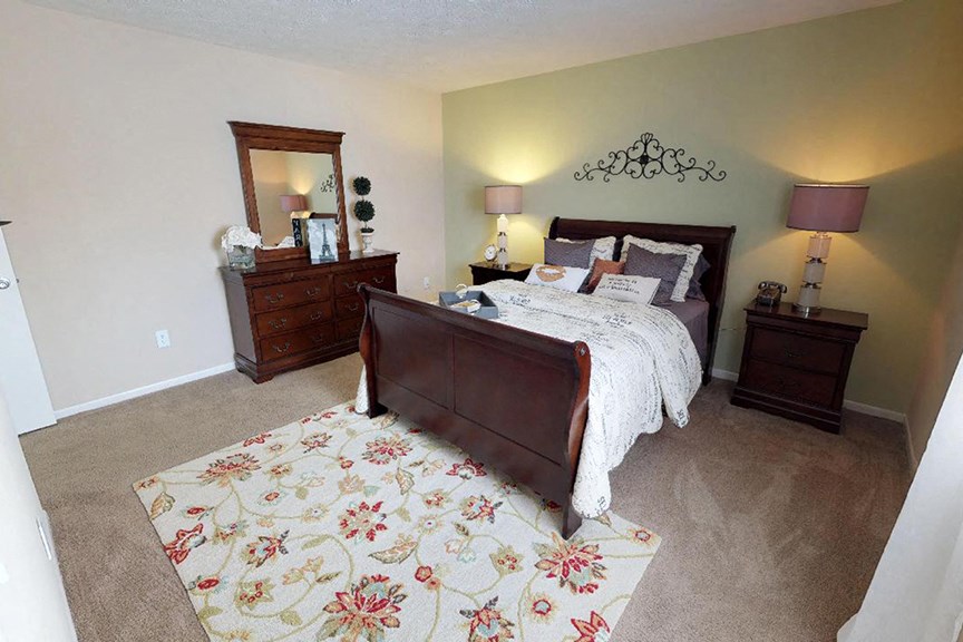 a bedroom with a bed and two dressers  at Hunter's Creek Apartments, Ohio, 45242