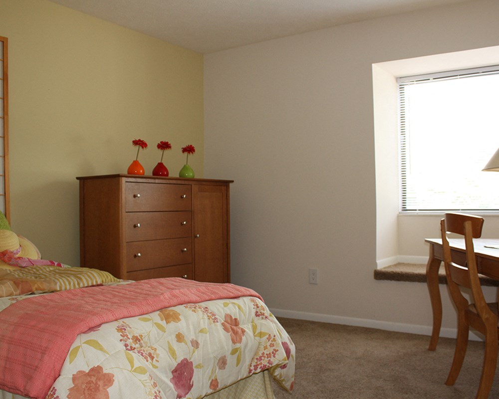 a bedroom with a bed and a dresser and a window  at Hunter's Creek Apartments, Ohio