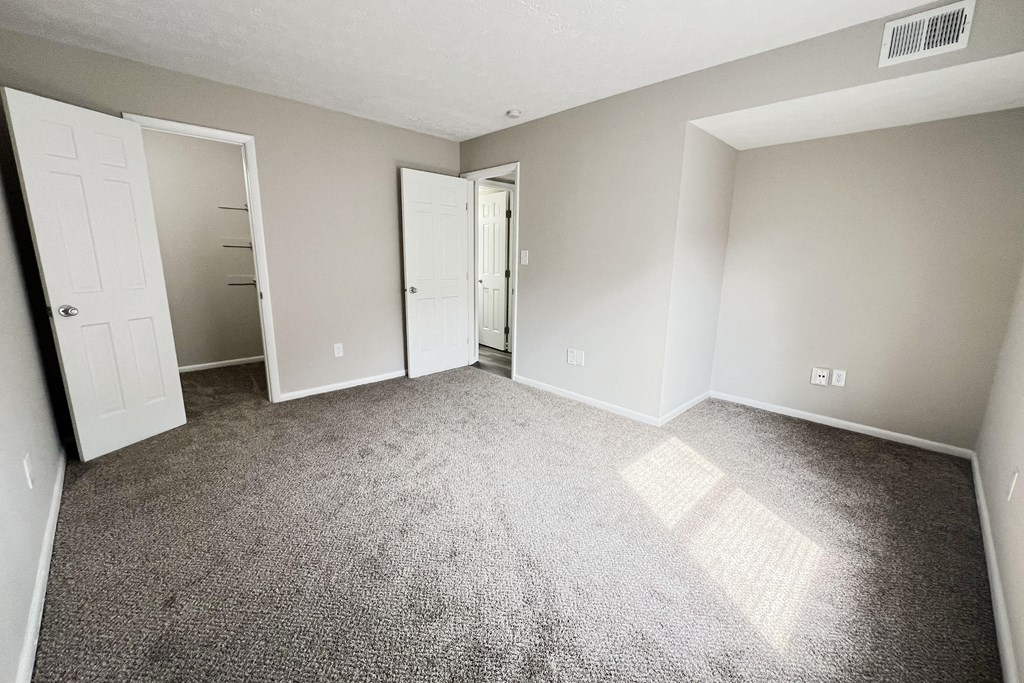 an empty living room with carpet and white doors at Revere Village Apartments, Centerville, 45458