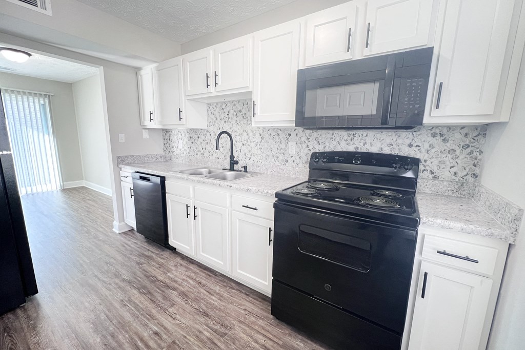 A kitchen with black appliances and white cabinets.