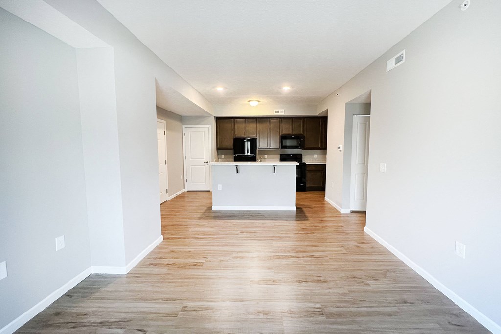 an empty living room and kitchen with white walls and wood flooring  at Brookfield Village Apartments, Ohio