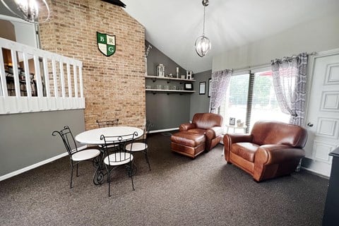 a living room with leather chairs and a table and a brick wall