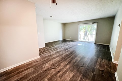 an empty living room with wood flooring and a sliding glass door at Crown Crossing Apartments, Amelia, Ohio