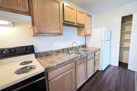 A kitchen with wooden cabinets and a white stove top oven at Crown Crossing Apartments, Amelia, Ohio, 45102
