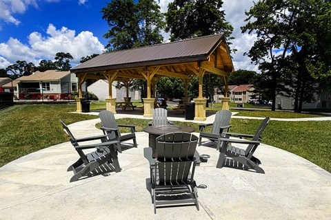 A gazebo with four chairs and a table is surrounded by trees.