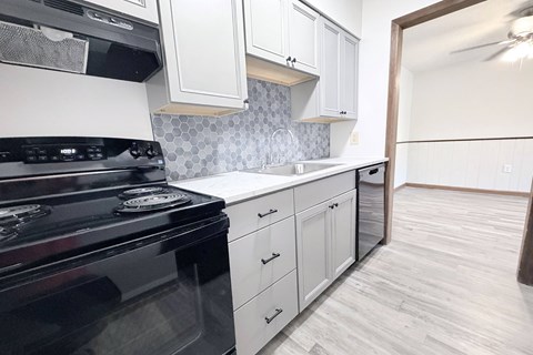 A kitchen with a black stove top oven and white cabinets.