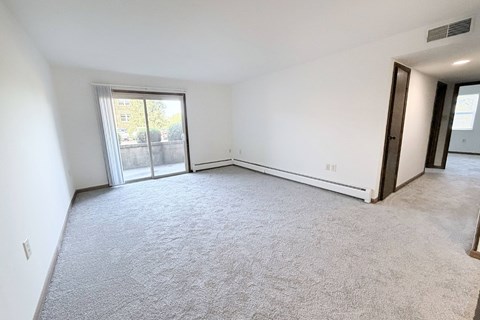 A spacious room with a carpeted floor and sliding glass doors leading to a balcony.