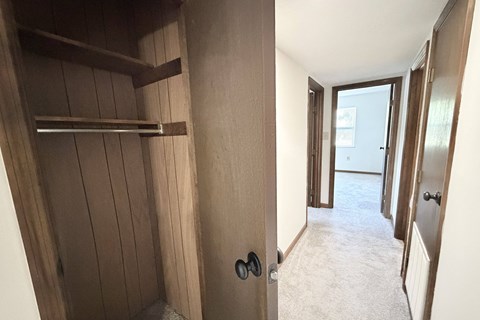 A hallway with a door on the right and a shelf on the left.