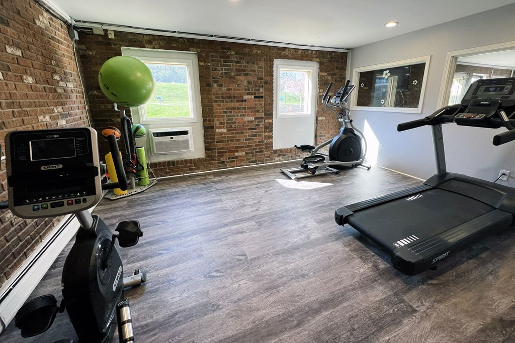 a gym with a brick wall and a treadmill and exercise equipment at Crown Pointe Apartments, Kentucky