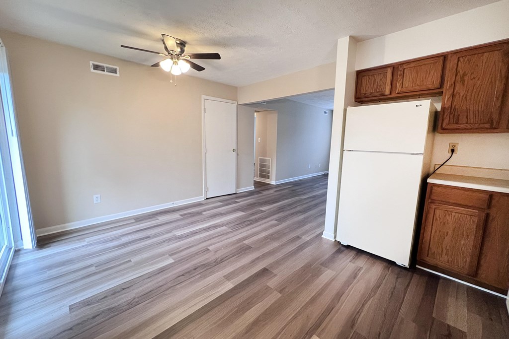 A room with a white refrigerator and wooden floors.