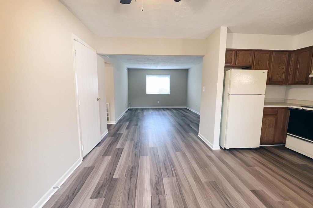A room with wooden flooring and a white refrigerator.