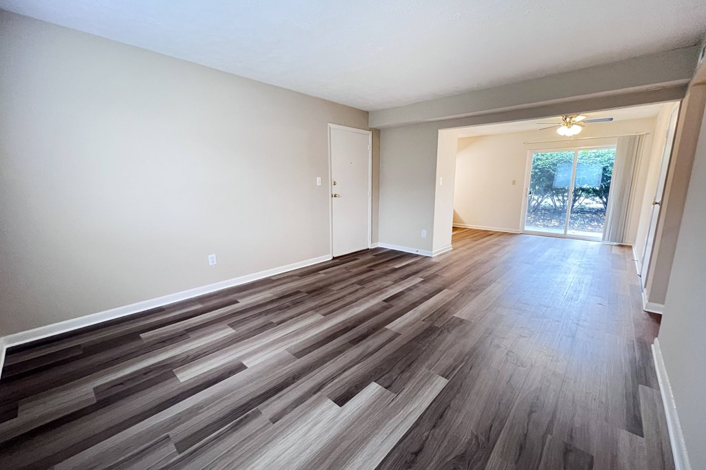 A room with a wooden floor and a door leading to a balcony.