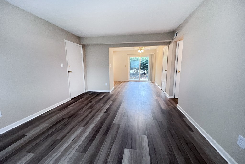 A room with a long hallway and a door at the end.