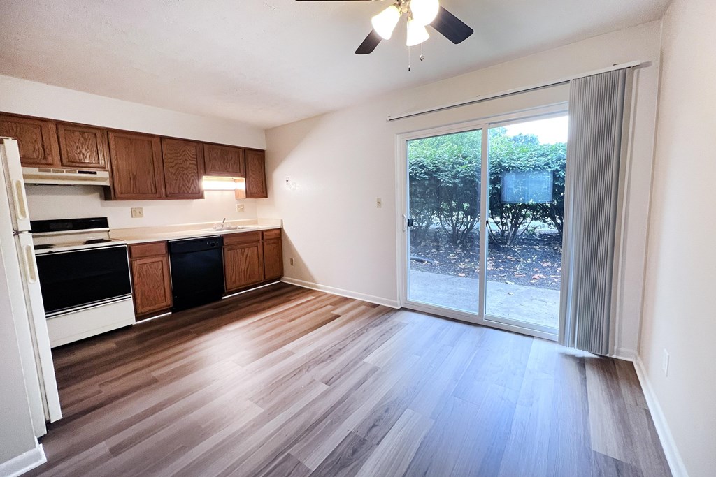 A kitchen with wooden floors and a ceiling fan.