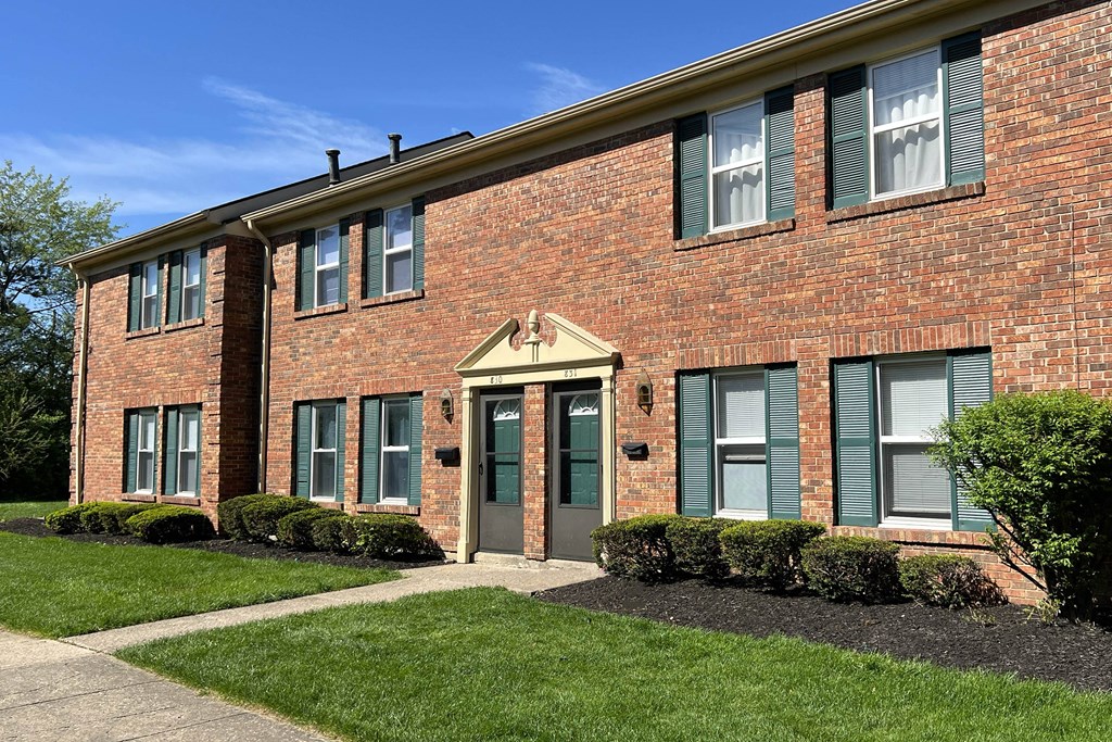 the front of a brick building with green shutters and grassat Revere Village Apartments, Ohio, 45458