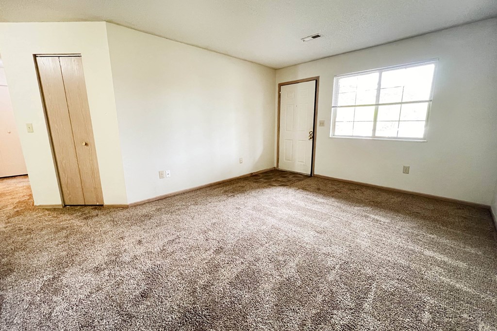an empty living room with carpet and a window at Eagle Crest Apartments, Galloway, 43119