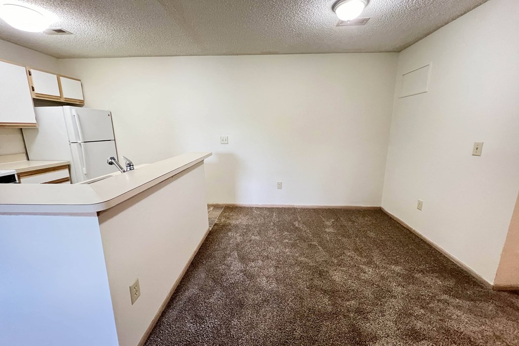 the living room of an apartment with a kitchen and a carpeted floor at Eagle Crest Apartments, Galloway
