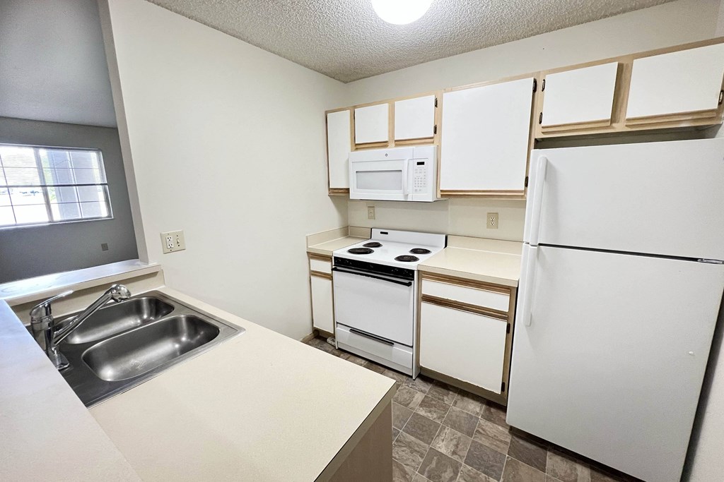 an empty kitchen with white appliances and white cabinets at Eagle Crest Apartments, Galloway, OH 43119