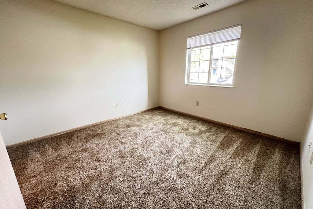 an empty bedroom with carpet and a window at Eagle Crest Apartments, Ohio, 43119