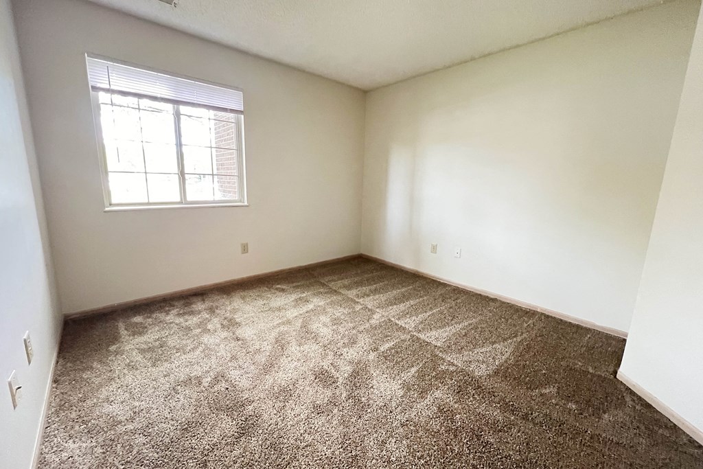 an empty bedroom with carpet and a window at Eagle Crest Apartments, Ohio, 43119