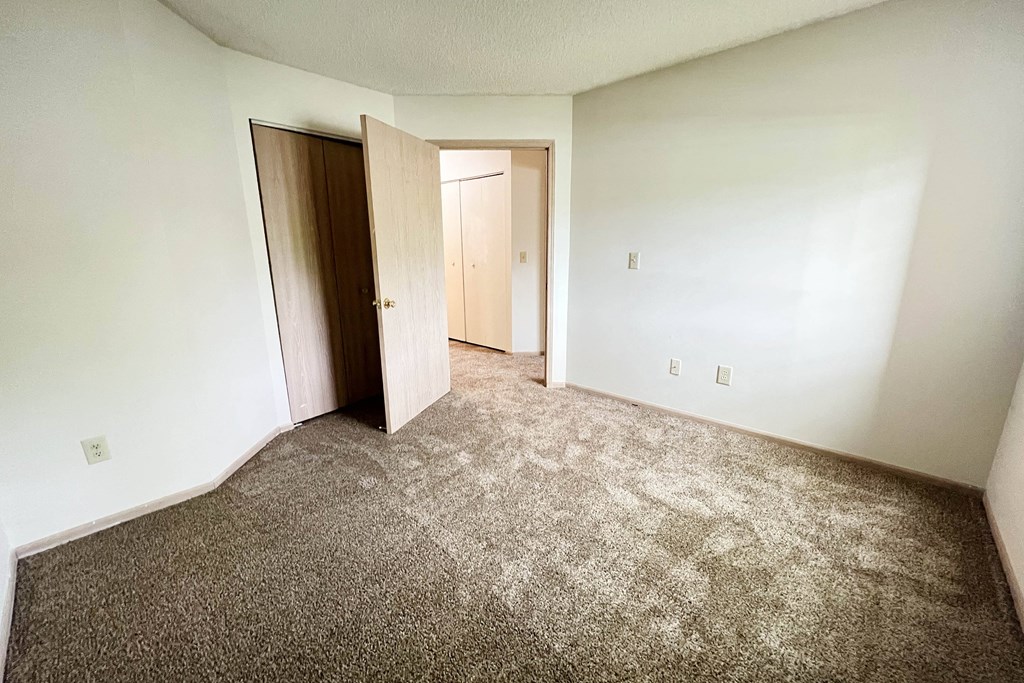 an empty room with carpet and a door to a closet at Eagle Crest Apartments, Galloway, Ohio