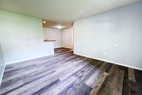 the living room and dining room of an apartment with wood flooring