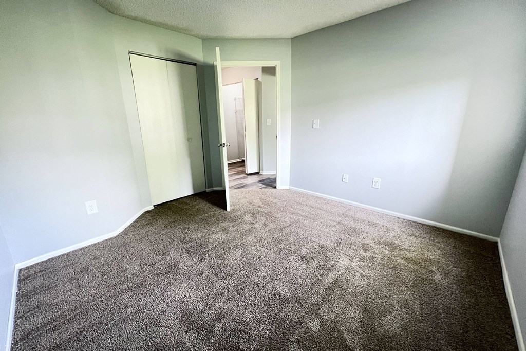 an empty room with carpet and a door to a hallway at Eagle Crest Apartments, Galloway, OH 43119