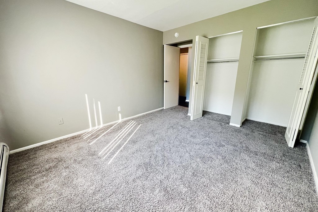 an empty room with a carpeted floor and three closets