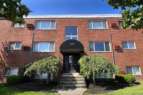 a brick building with a black awning and two trees in front at Crown Court Apartments, Kentucky, 41042