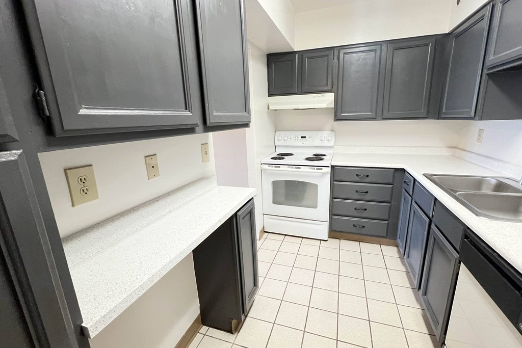 a kitchen with black cabinets and white appliances and a sink at Indian Lookout Apartments, Cincinnati