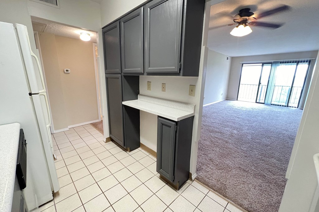 a kitchen with black cabinets and an empty living room with a ceiling fan at Indian Lookout Apartments, Cincinnati, 45238