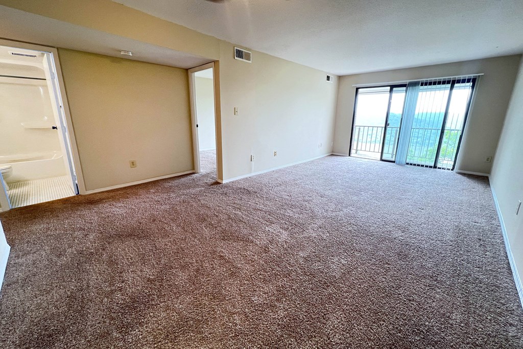 an empty living room with a door to a balcony at Indian Lookout Apartments, Cincinnati
