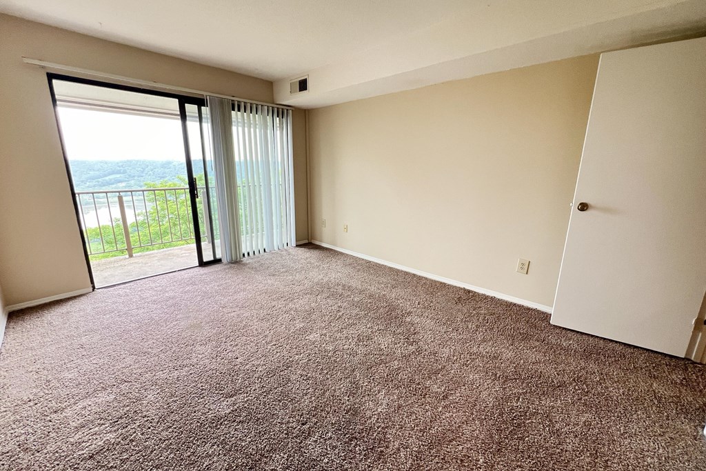 an empty living room with a sliding glass door to a balcony at Indian Lookout Apartments, Cincinnati, Ohio