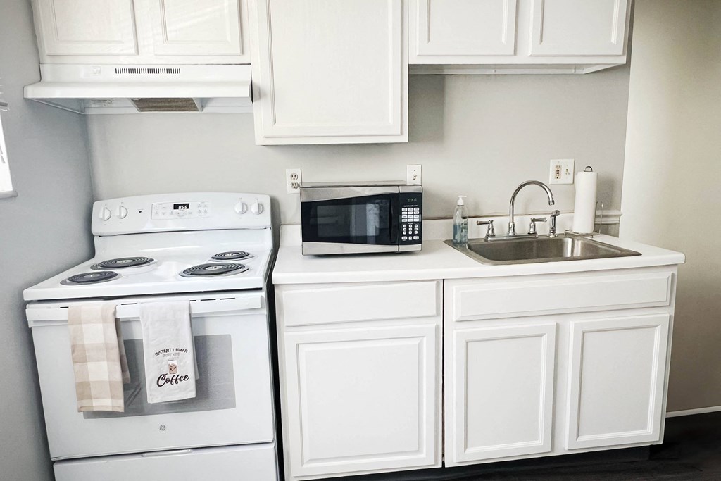 a kitchen with white cabinets and a sink and a stove