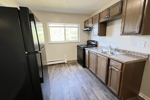 an empty kitchen with wooden cabinets and a black refrigerator at Crown Court Apartments, Kentucky, 41042