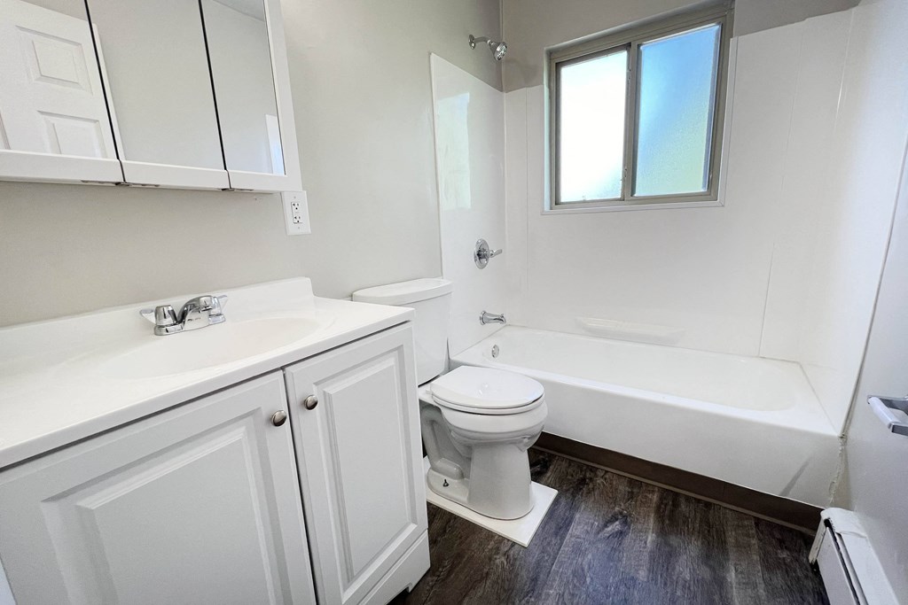 a bathroom with white cabinets and a toilet and a bath tub
