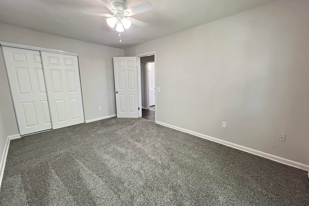 an empty living room with carpet and a ceiling fan