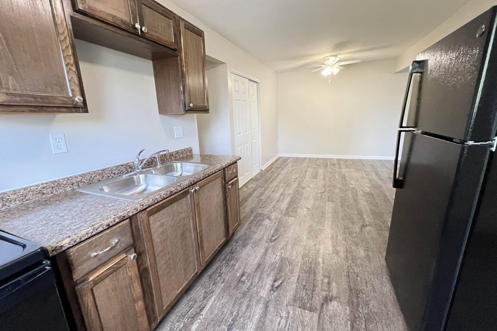 a kitchen with wooden cabinets and a stainless steel sink and refrigerator