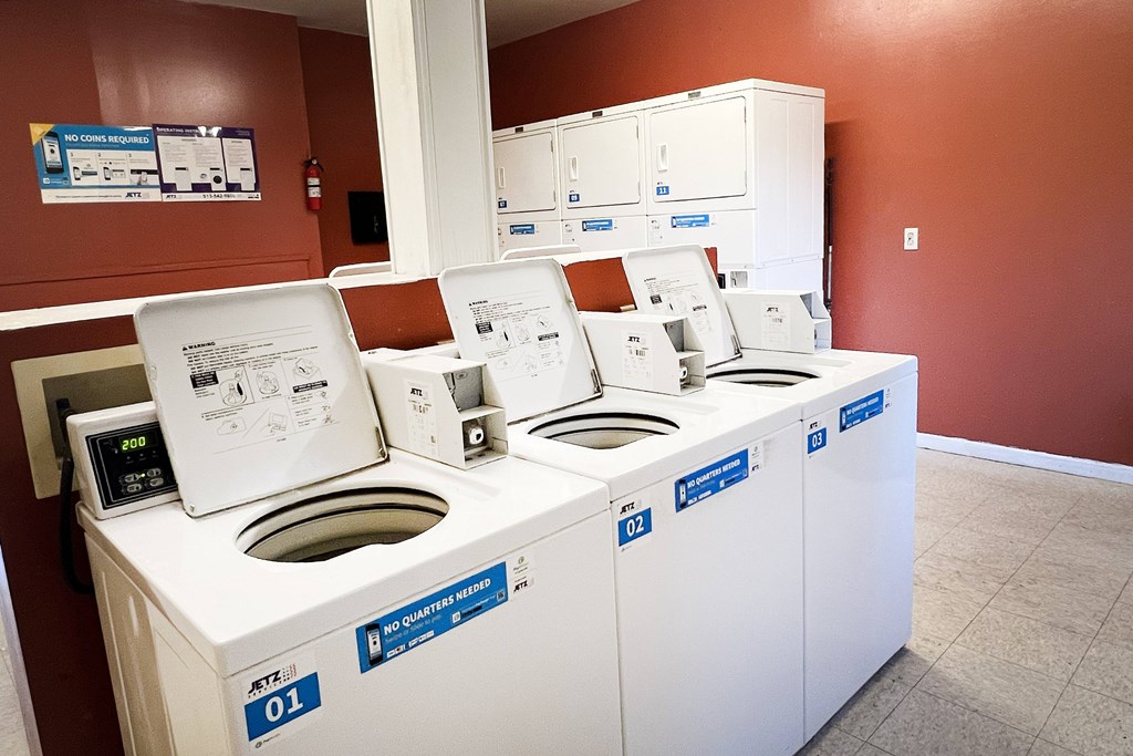 A row of white washing machines are lined up in a room.